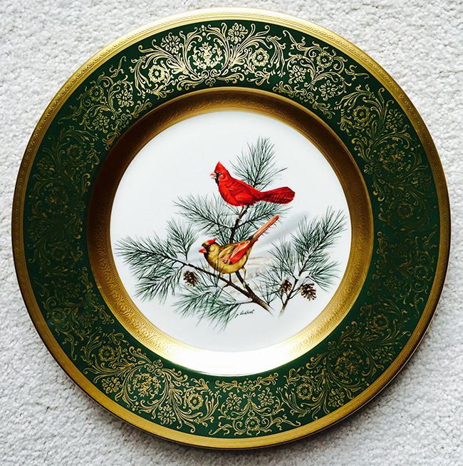 Male and female cardinal on pine tree branches painted in center of green white and gold dinner plate