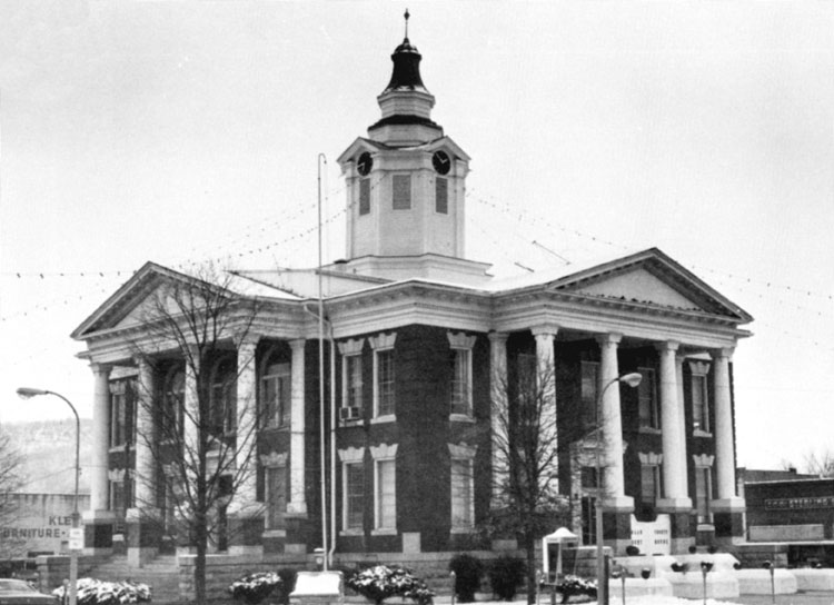 Two-story building with central clock tower and identical columned entrances