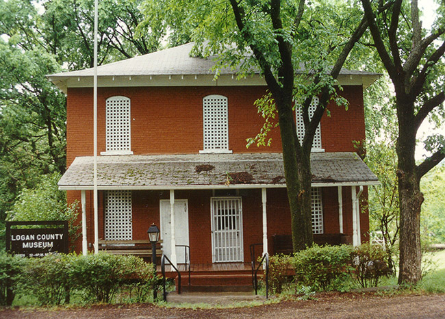Two-story brick building with tree and sign "Logan County Museum"