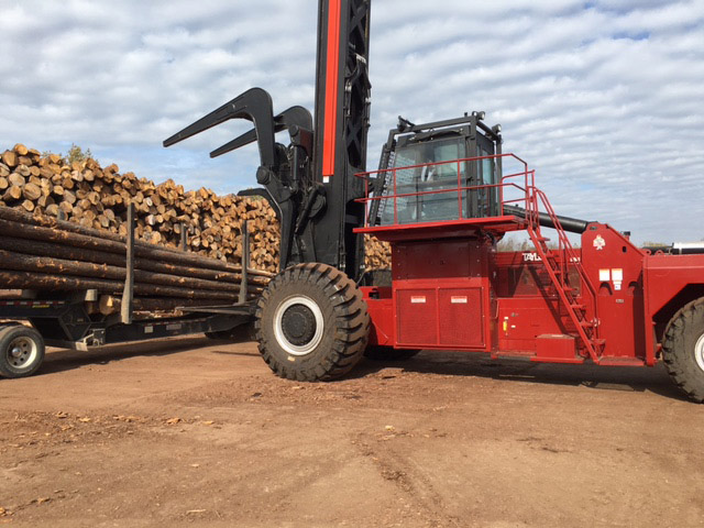 Tractor picking up logs from trailer