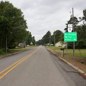 Two-lane road with road signs and single-story buildings in the distance