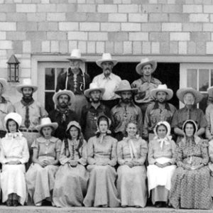 Group of white men and women in pioneer costumes including hats and bonnets