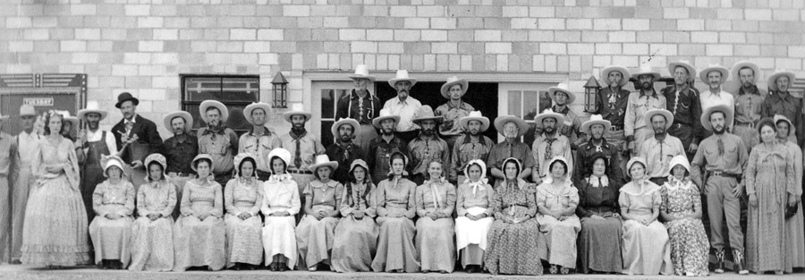 Group of white men and women in pioneer costumes including hats and bonnets