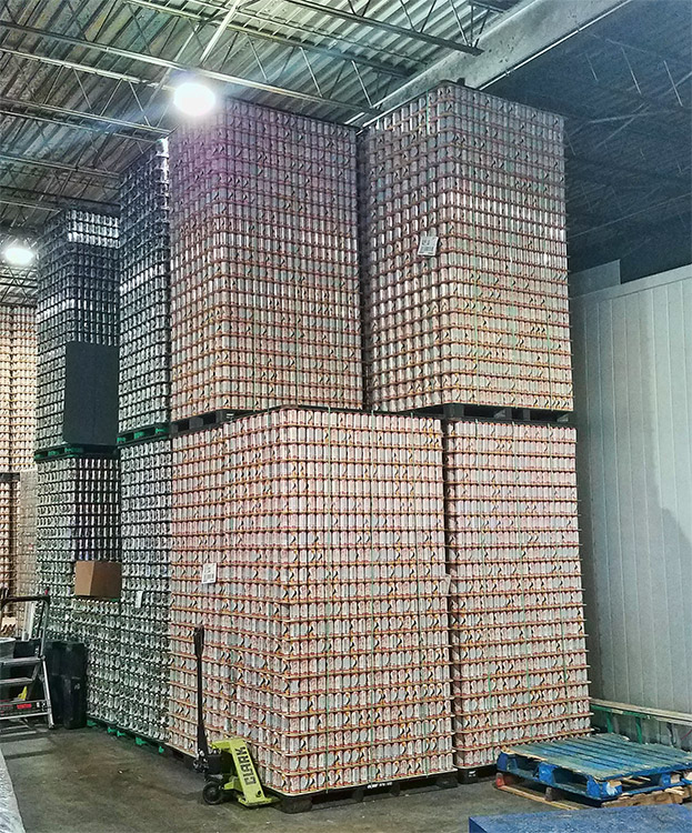 Stacks of beer cans on wooden pallets inside warehouse