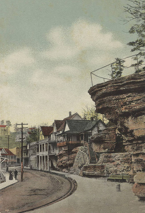 Rock outcropping over residential road with multistory houses