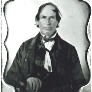White man with neck-length hair in suit and bow tie