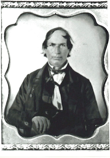 White man with neck-length hair in suit and bow tie