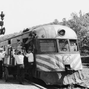 White men wearing white shirts and hats loading a train car