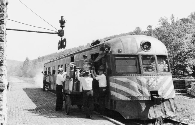 White men wearing white shirts and hats loading a train car