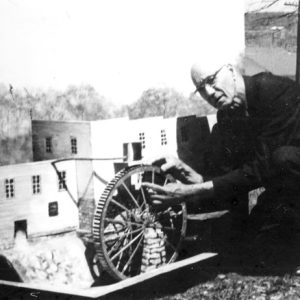 white man operates model of mill