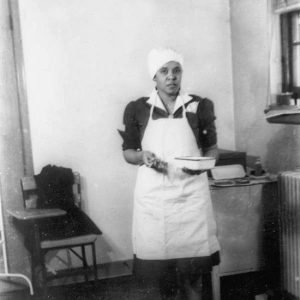 African-American woman in cap and apron holding medical utensils