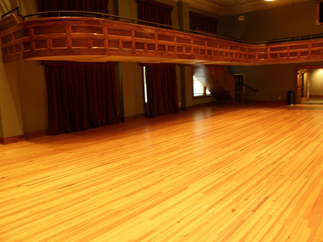 Ballroom with waxed wood floor and balcony with red curtains