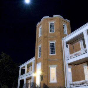 Two-story brick building with three-story central tower at night