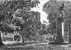 Brick building with central tower and park with trees and monument featuring charging soldier