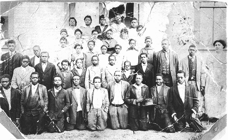 Group of African Americans seated and standing in front of building