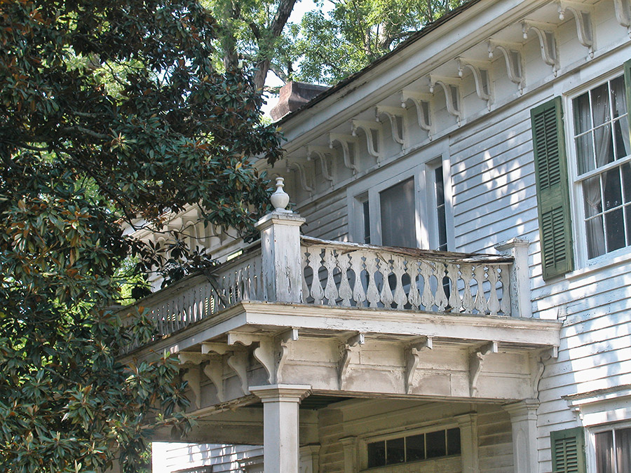 Balcony on two-story house with nearby tree
