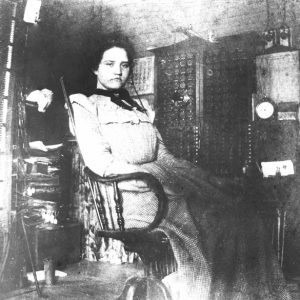 White woman sitting in a chair with telephone switchboard