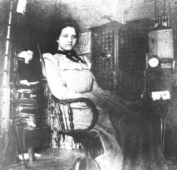 White woman sitting in a chair with telephone switchboard