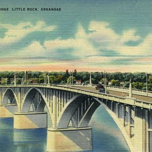 Concrete arch bridge over river with town buildings and trees in the background on post card