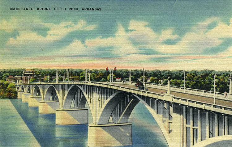 Concrete arch bridge over river with town buildings and trees in the background on post card