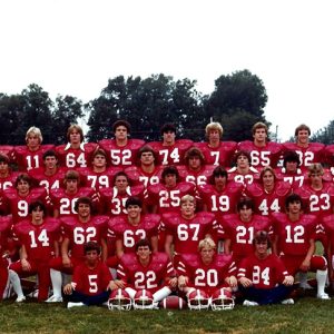 Group of young men in red football uniforms and their coaches
