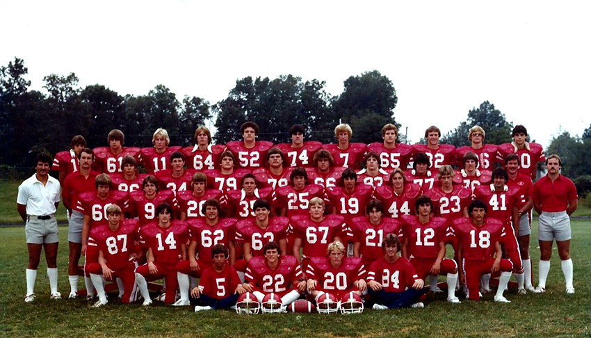 Group of young men in red football uniforms and their coaches