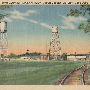 Factory buildings and water towers on grass with railroad tracks in the foreground on post card