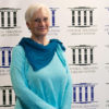 white woman with white hair wearing glasses in blue shirt and pants