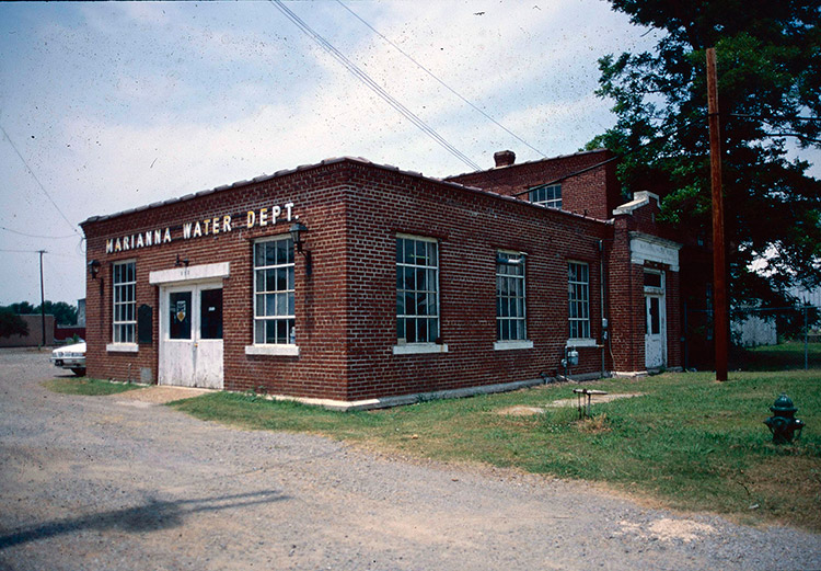 Brick water department building with single-story extension on gravel parking lot