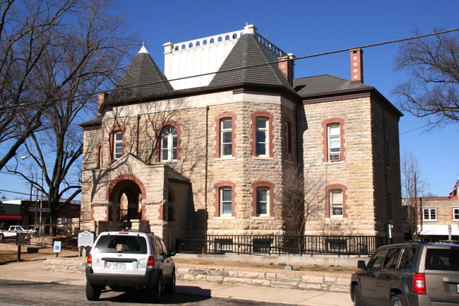 two story stone building with cars parked in front