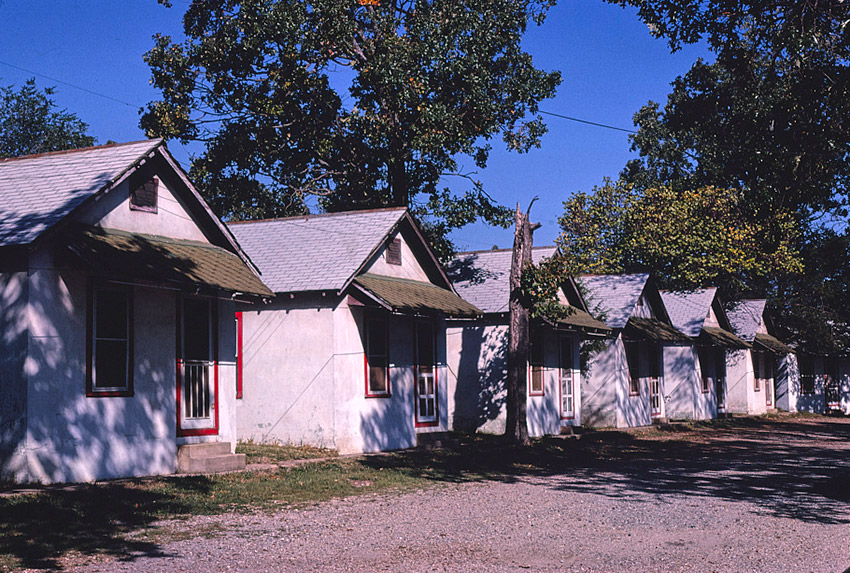 Row of identical single-story housing units on gravel road