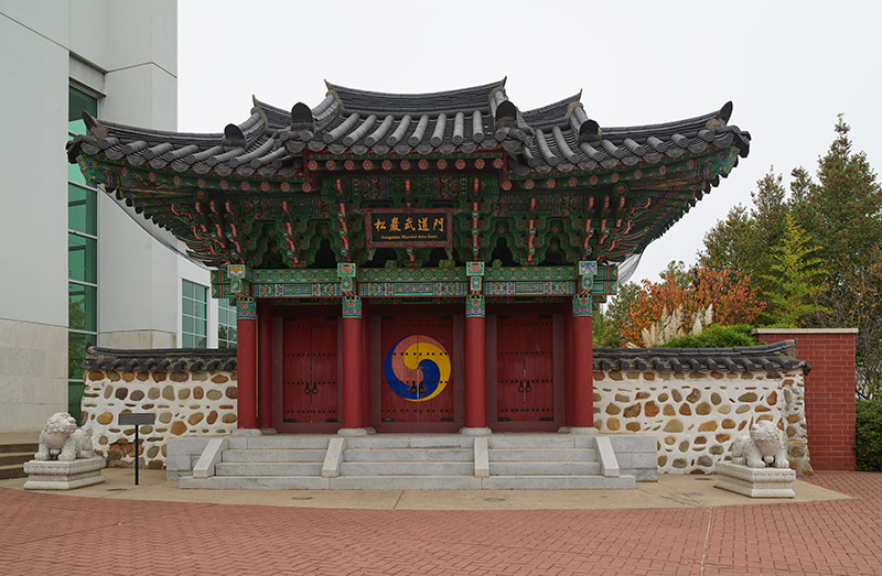 Memorial East Asian style gate on steps next to multistory building