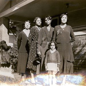 African-American women and girl outside house