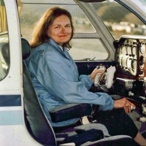 White woman sitting in pilot's seat of airplane