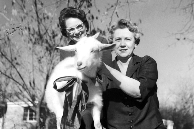 Two older white women posing with a goat
