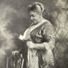 African American woman in fancy dress standing by a chair