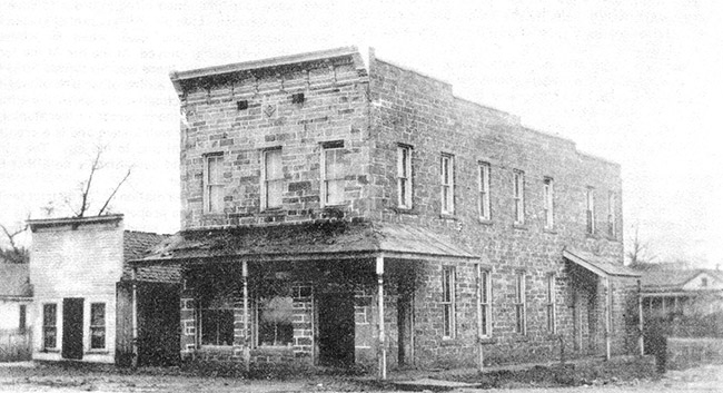 Two-story brick building and storefront on dirt road