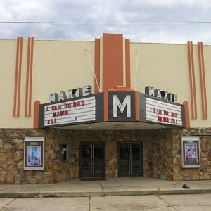 "Maxie" theater building with stone walls orange trim and marquee