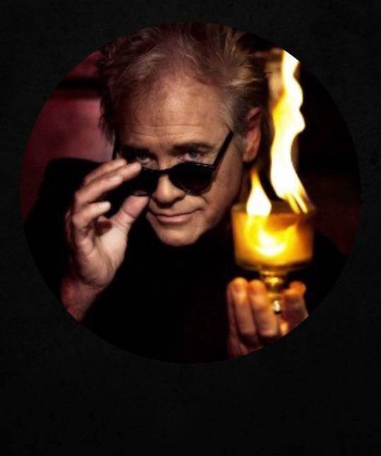 White man with sunglasses holding a glass cup with fire in it