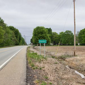 "McArthur" road sign next to two-lane highway
