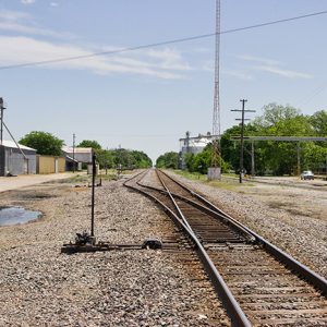 Railroad tracks on gravel with industrial buildings on both sides