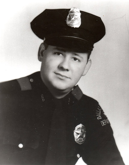 dark-eyed white man in police uniform with cap and badge