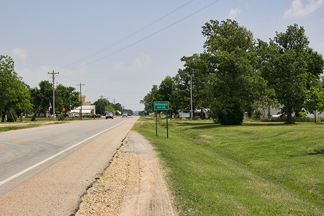 Street with green "McDougal" sign and green trees and grass