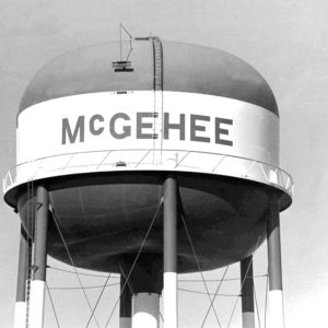 top of massive water tower with seven legs ladders and surrounding walkway painted "McGehee" in large letters.