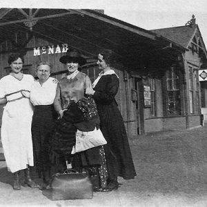 Four white women posing together at train depot building