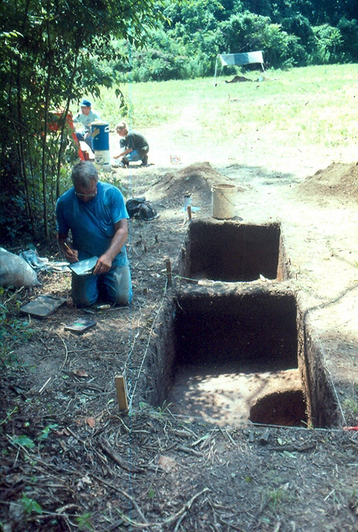 White men and woman documenting a dig site near mounds
