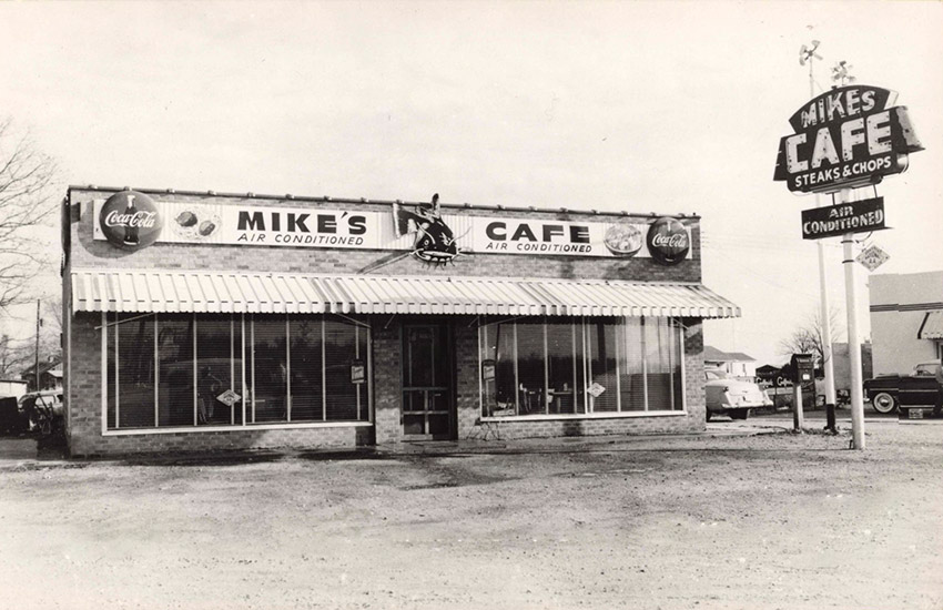 Single-story building with awning next to "Mike's Cafe"  sign