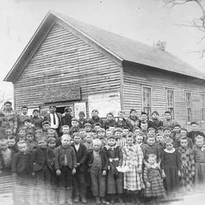 Group of white children outside single-story school building