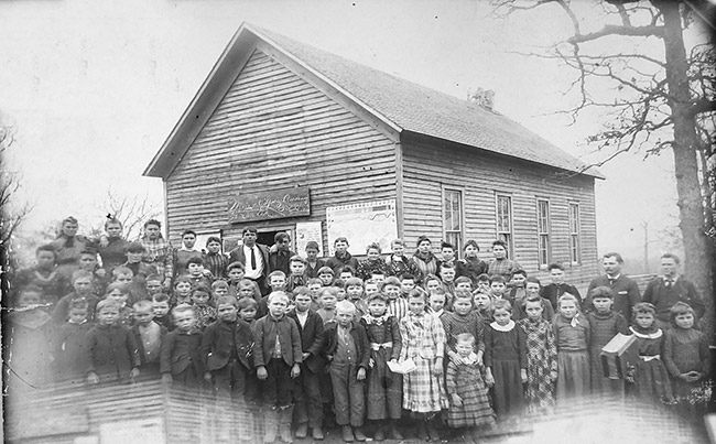Group of white children outside single-story school building