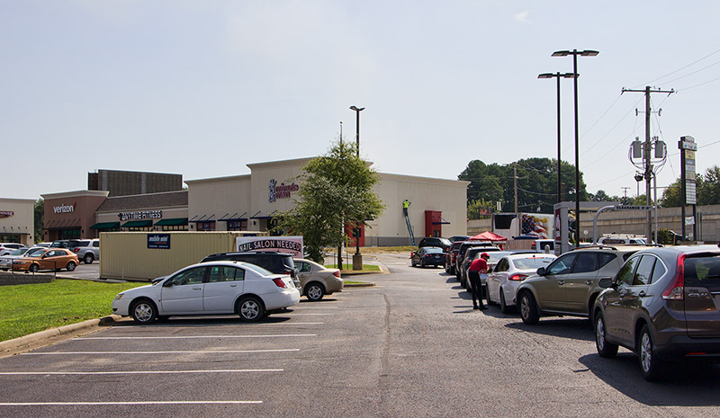 Line of cars and parked cars in strip mall parking lot